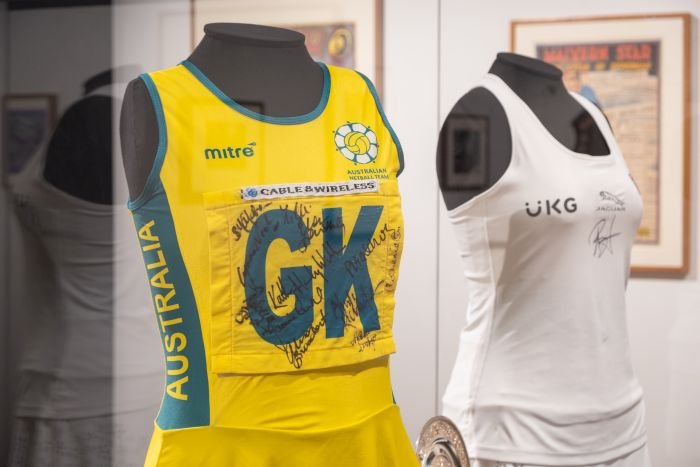 A mannequin with a yellow netball dress and a mannequin with a white tennis outfit.