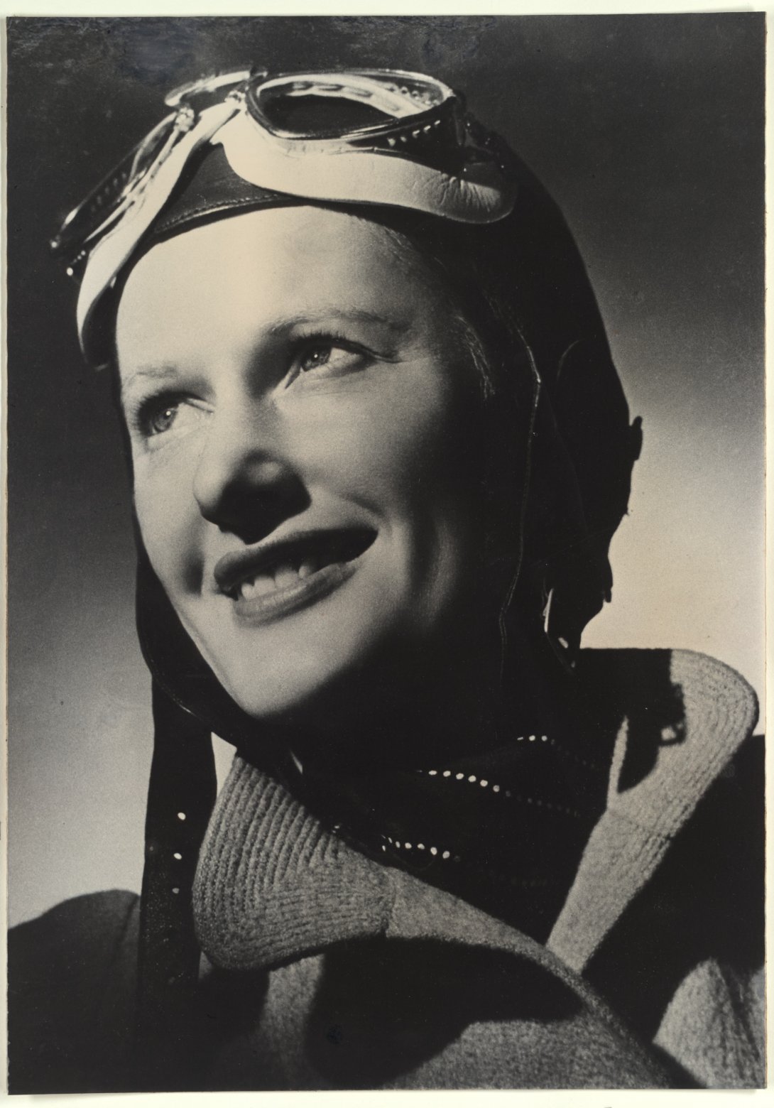 Portrait of a smiling woman wearing a pilot's cap and googles