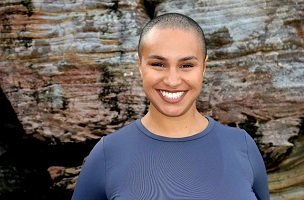 Celeste Carnegie standing with a large smile in front of a rock face