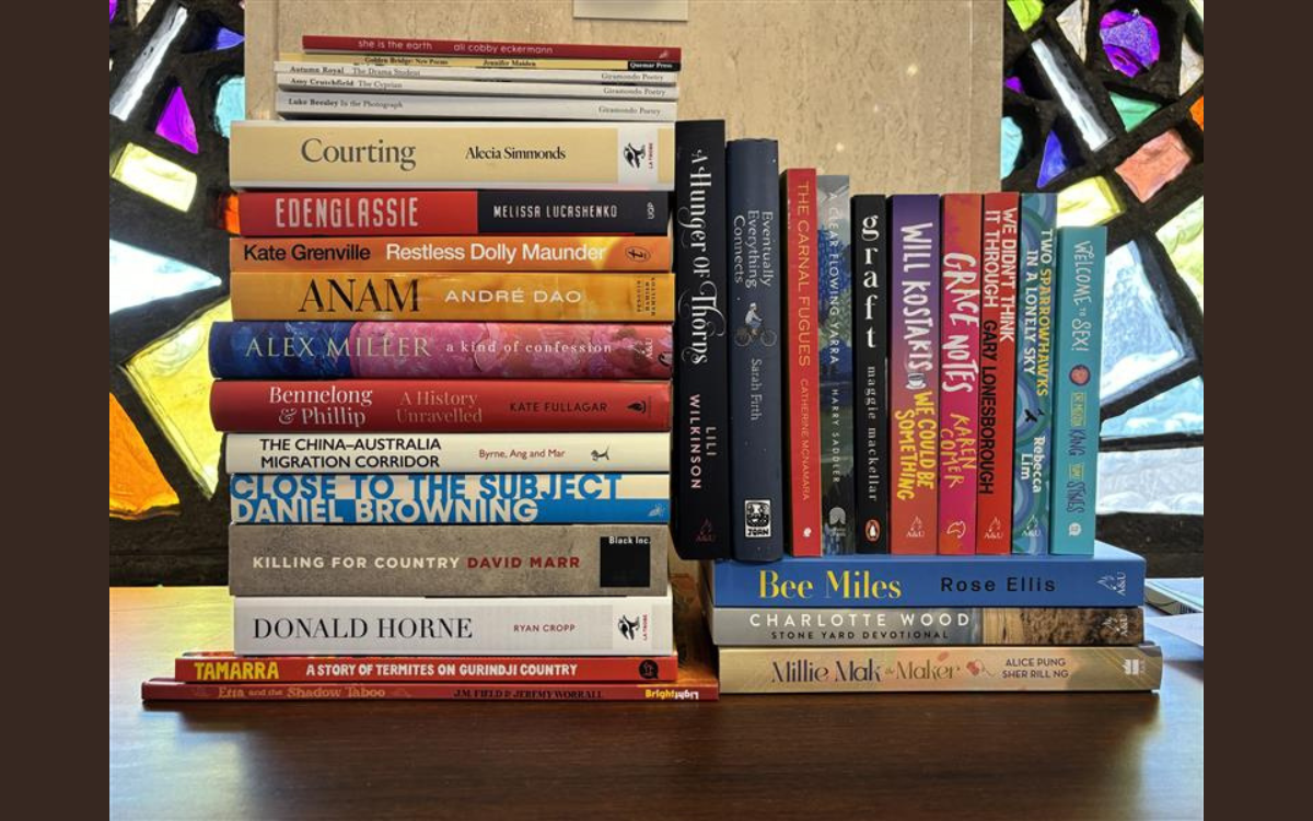 A stack of books in front of stained glass windows.