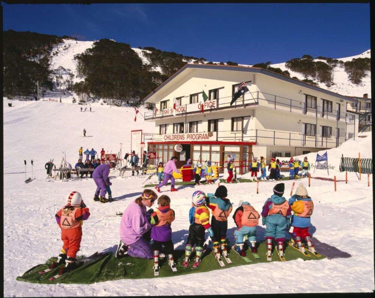 A photo of Falls Creek ski resort with several children being taught how to ski.