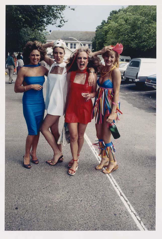 Four women smiling and laughing in a street wearing Melbourne Cup attire