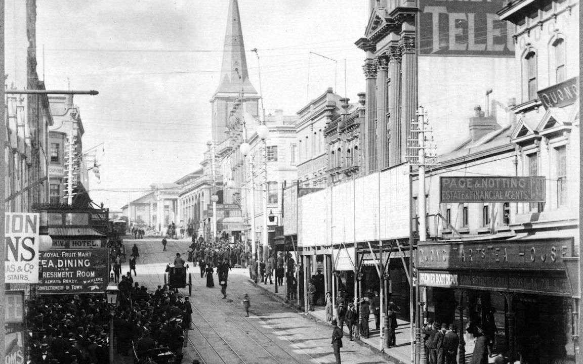 Building-lined street with many people and carts moving down the side