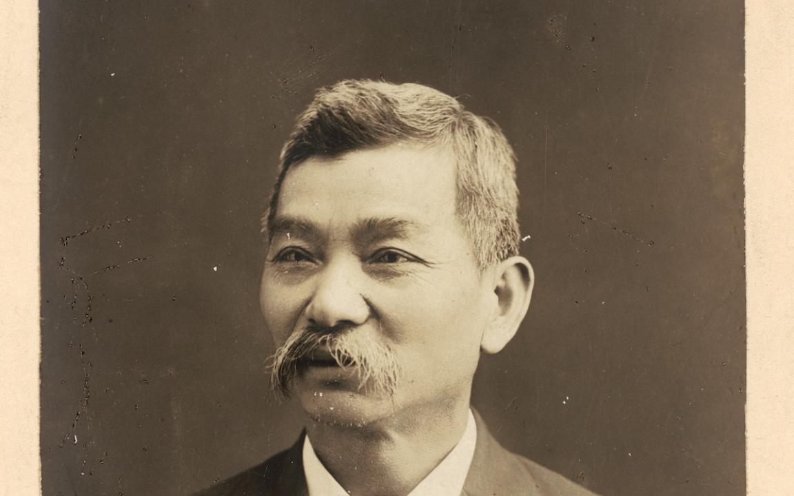 Portrait of a Chinese-Australian man with a moustache and wearing a nice suit