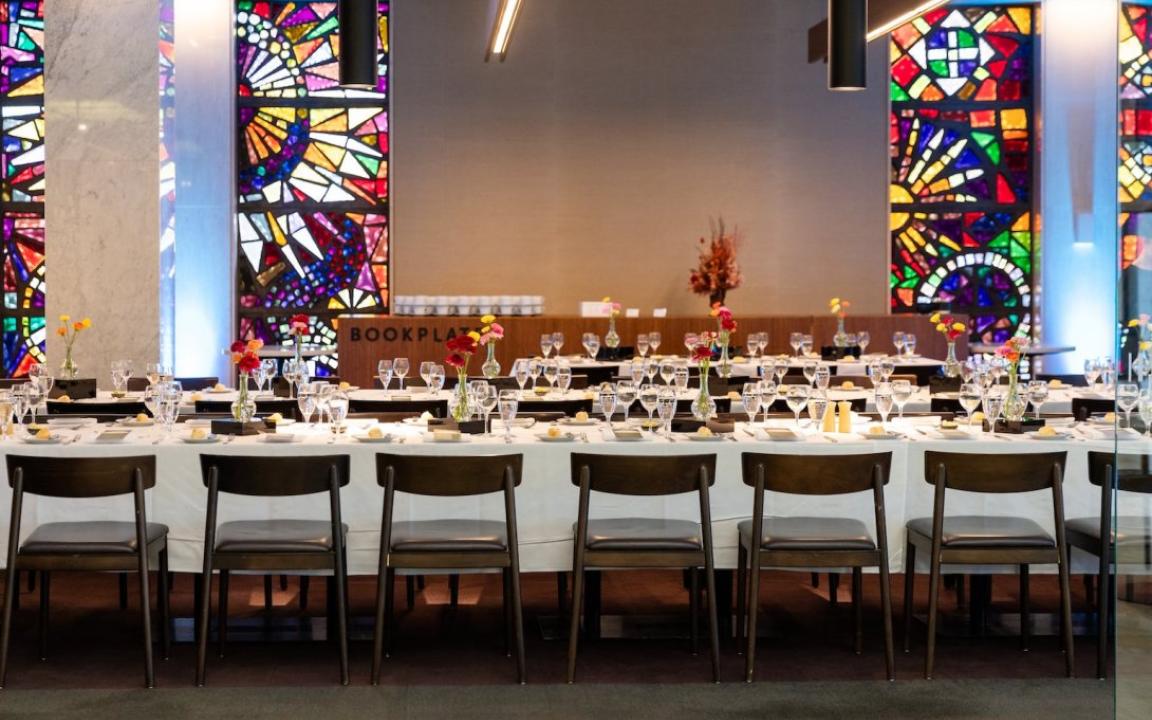 Bookplate cafe at the Library set up with long tables set with white table cloths, wine glasses and flowers