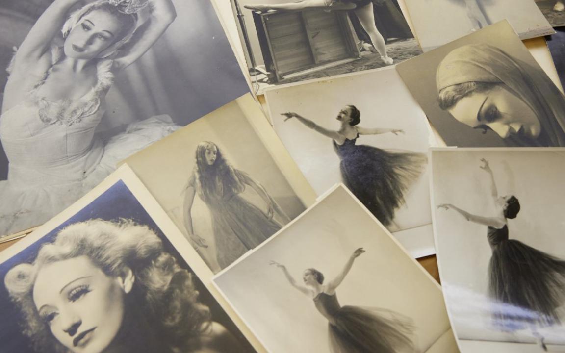 Photographs spread on a table, of a woman throughout her career in ballet, including photos of her dancing and portraits