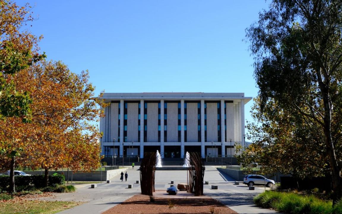 Front of the National Library building from the park across the road. The Library building is made of marble and concrete, and has large pillars along the front. It's a sunny day, and the trees are starting to change colours