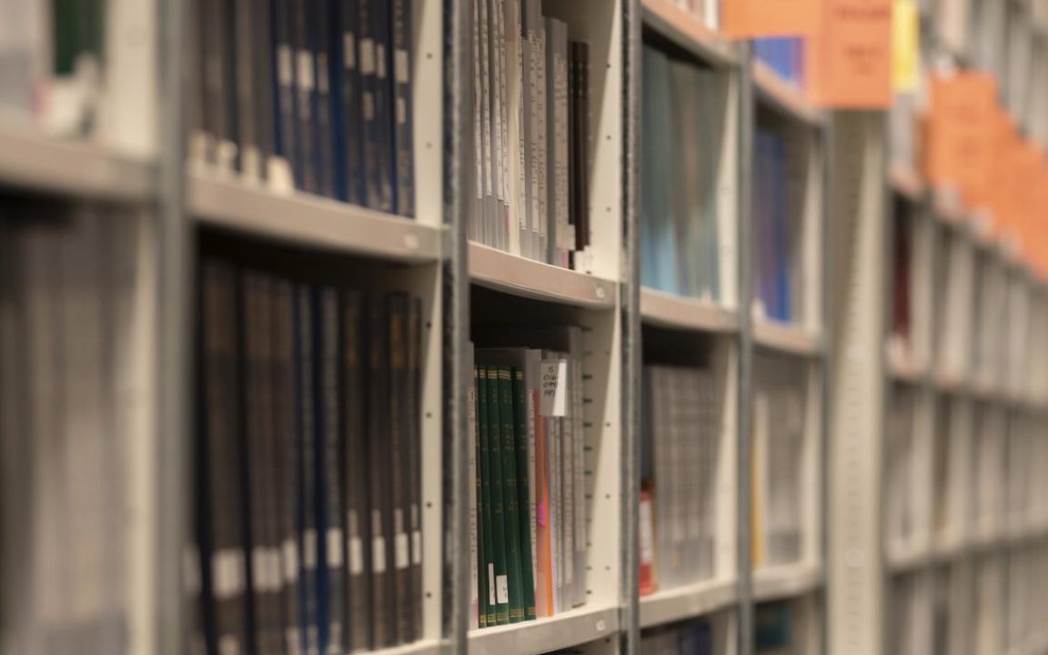 Long shelves of books and other print material with regular orange signs