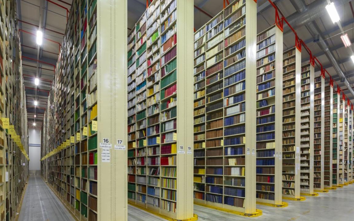 Rows of very tall, large bookshelves (stacks) in a warehouse