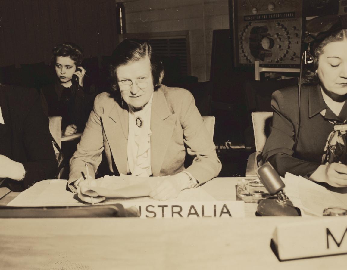 Jessie Street sitting at a desk with papers and a small label reading 'Australia' in front of her