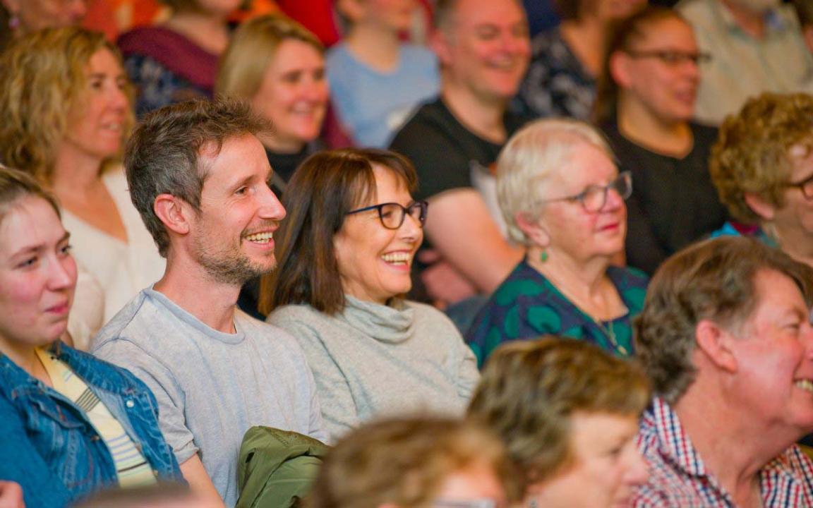 A crowd of people sitting and looking at something out of frame.