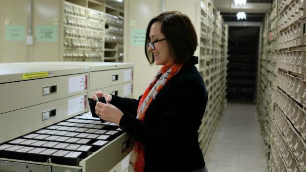 Woman looking at items in a filing cabinet in library stacks