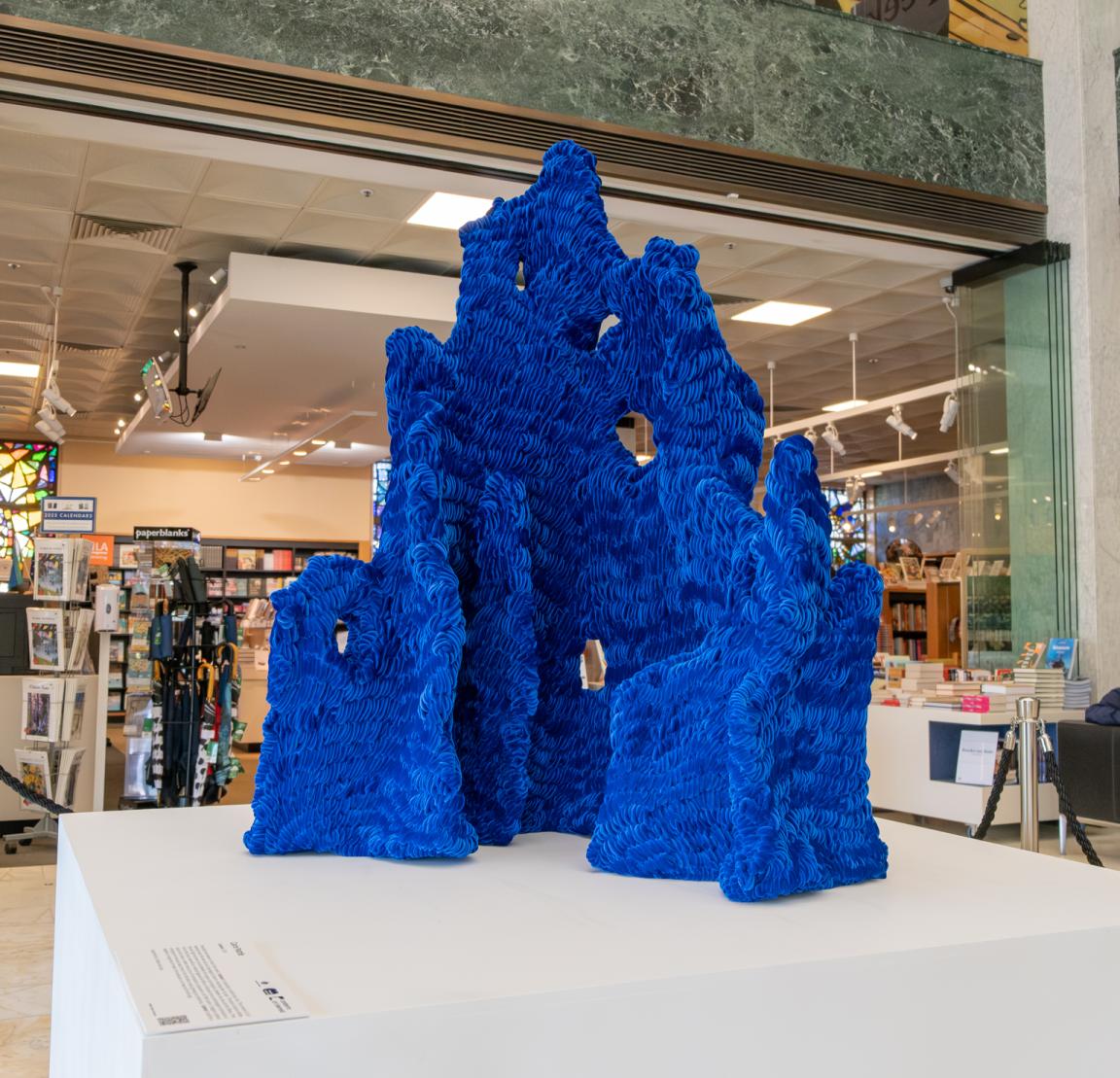 Blue velvet structural artwork on a white pedestal in the Library foyer