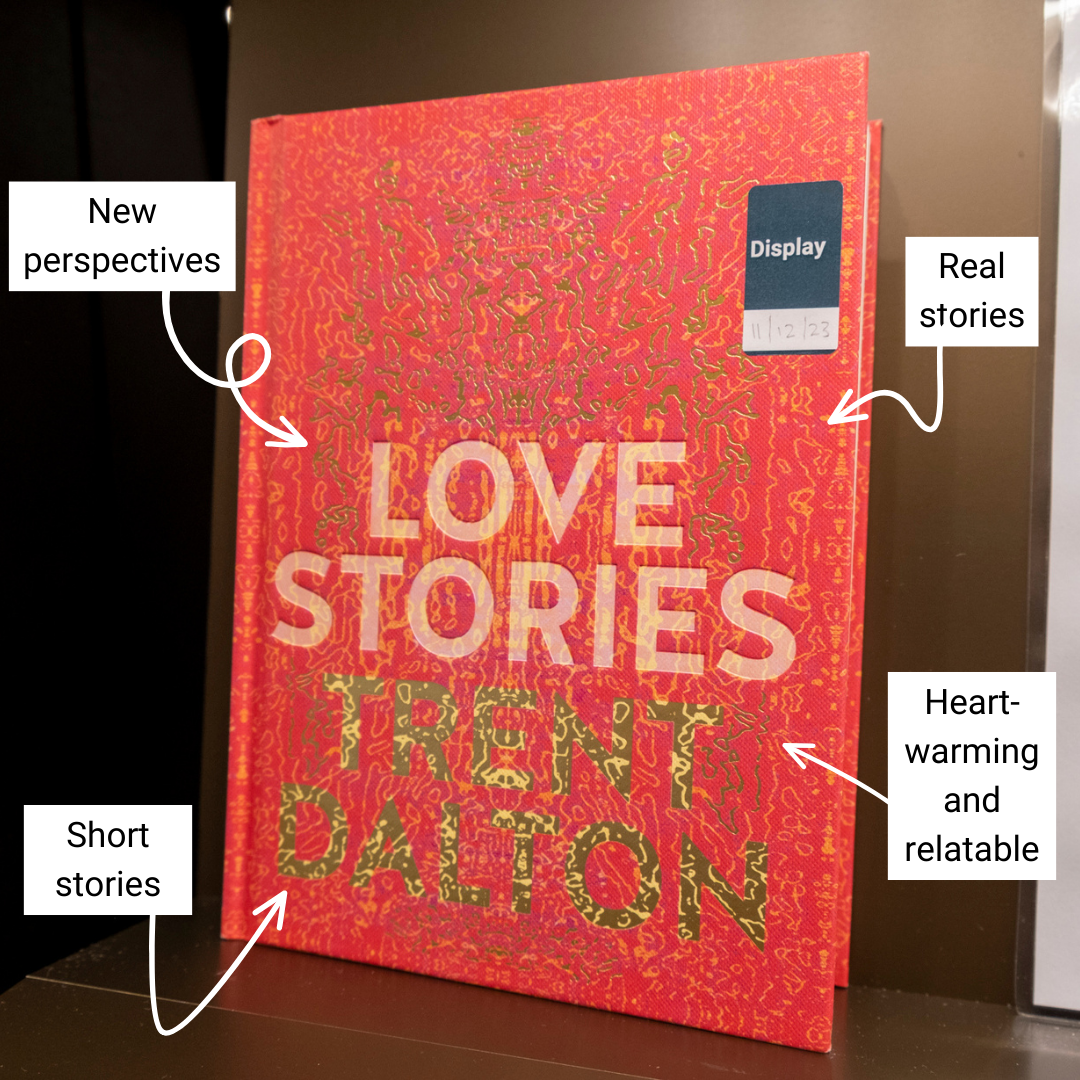 Hardback book with patterned red cover with text reading 'Love Stories' and 'Trent Dalton' sitting on display on a shelf. Around the book are annotated reading 'new perspectives', 'heart-warming and relatable', 'real stories' and 'short stories'