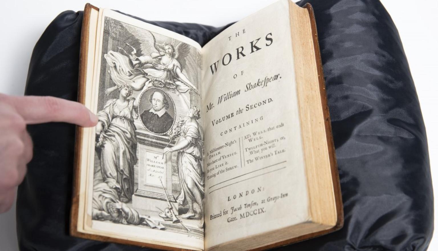 Old book open with one page showing black and white illustration of a shrine for Shakespeare and the other page reading 'The Works of Mr William Shakespear'